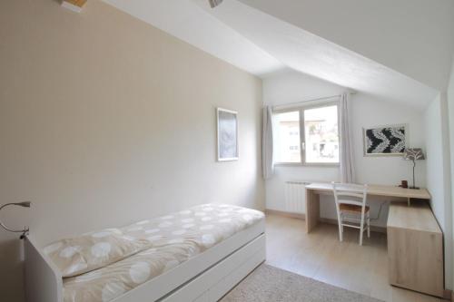 a white bedroom with a bed and a desk at Pretty terraced house with garden level and garage in Aix-les-Bains