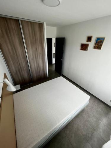 Cette chambre comprend un lit blanc et une porte en bois. dans l'établissement Le Mérida, à Juvignac