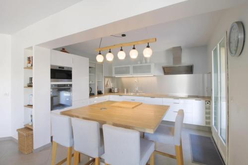 a kitchen with a wooden table and white cabinets at Pretty terraced house with garden level and garage in Aix-les-Bains