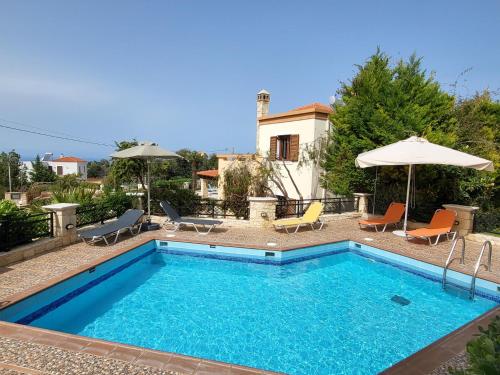 una piscina con sillas y sombrillas junto a una casa en Agnanti Despoina villa with private pool, en Skouloúfia