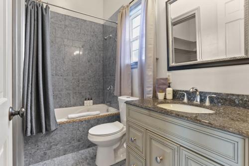 a bathroom with a toilet and a sink and a tub at 3BD HOME STEPS TO SAINT CHARLES Gated Parking in New Orleans