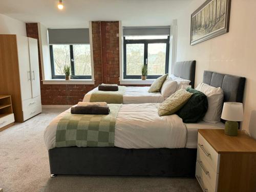 1 Schlafzimmer mit 2 Betten und 2 Fenstern in der Unterkunft Stunning 2 Bed Apartment In Bradford City Centre With Free Parking in Bradford