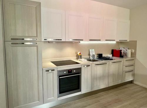 uma cozinha com armários brancos e um forno com placa de fogão em Ascona: ORTO DEGLI ANGIOLI em Ascona