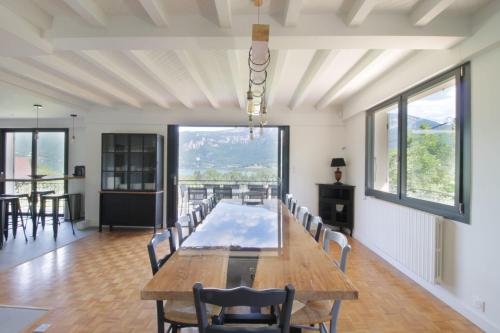 un comedor con una gran mesa de madera y sillas en Beautiful villa on the slopes of Lake Aiguebelette!, en Saint-Alban-de-Montbel