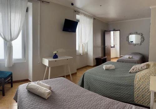 a hotel room with two beds and a mirror at Residência Aviz in Peniche