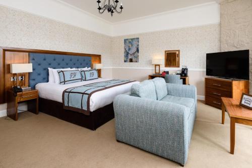 Schlafzimmer mit einem Bett, einem TV und einem Stuhl in der Unterkunft Fisher's Hotel in Pitlochry