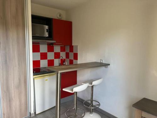 une petite cuisine avec un comptoir et deux tabourets dans l'établissement Le Curaçao, à Juvignac