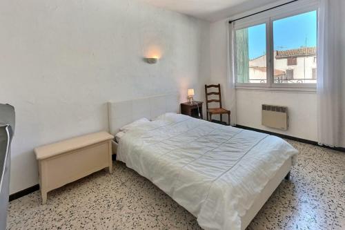 une chambre blanche avec un lit et une fenêtre dans l'établissement Mol, à Sérignan