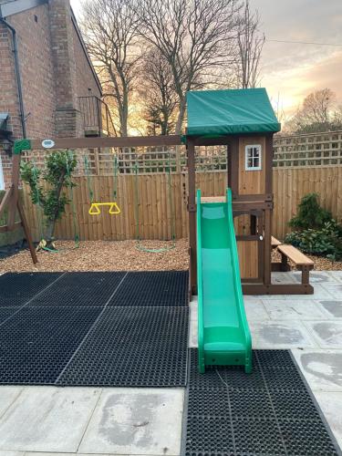 un parque infantil con un tobogán verde en el patio trasero en The Farm Burscough, en Burscough