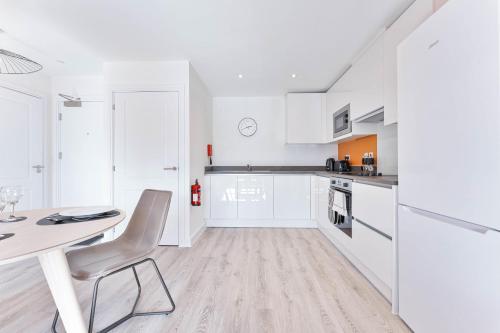 a kitchen with white cabinets and a table and chairs at StayZeni, Hardwick House Derby Modern 1 Bed Flat in Derby