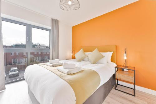 a bedroom with a large bed with an orange wall at StayZeni, Hardwick House Derby Modern 1 Bed Flat in Derby