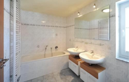a bathroom with two sinks and a bath tub and a tubermott at Stunning Apartment In Fuhlendorf With Lake View in Fuhlendorf
