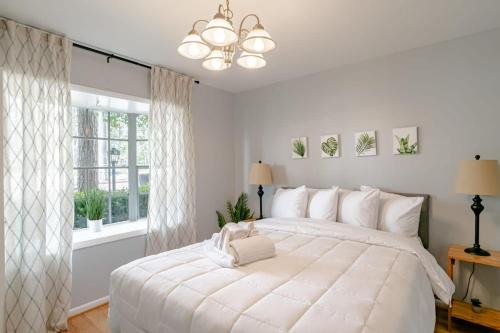 a white bedroom with a large white bed and a window at Private Pool & Yard Mins to Dining & University in Mobile