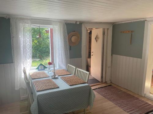 ein Esszimmer mit einem Tisch und einem Fenster in der Unterkunft Genuine 100 year old countryside cottage in Rimbo