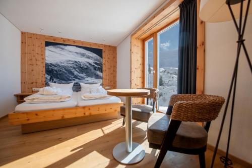 a bedroom with a bed and a chair and a window at Mondschein Hotel & Chalet in Stuben am Arlberg