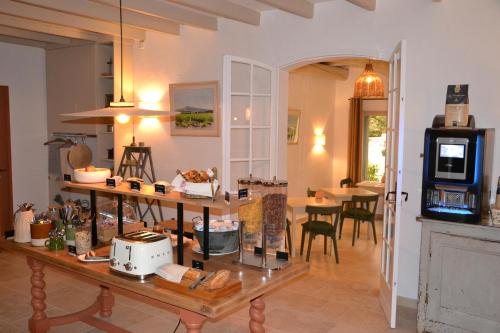 a living room with a table and a kitchen at Hôtel La Garrigue & Bar Le Perchoir in Venasque
