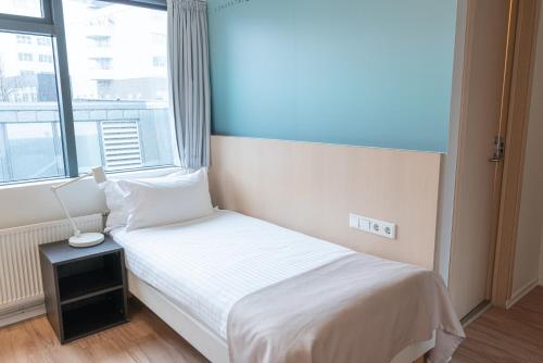a small bedroom with a white bed and a window at Reykjavik Lights Hotel by Keahotels in Reykjavík