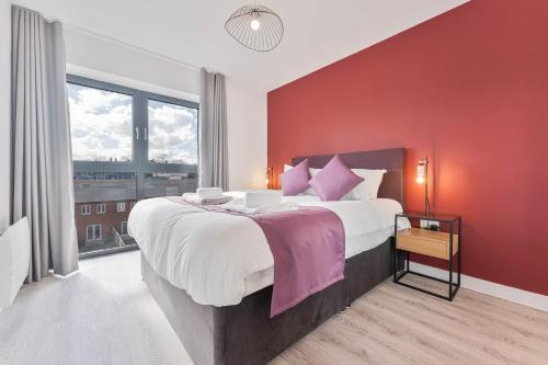 a bedroom with a large bed with a red wall at Stunning 1 Bed Apartment Nightingale Quarter Derby in Derby