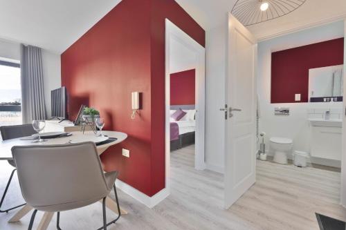 Cette chambre dispose d'un mur rouge, d'une table et de chaises. dans l'établissement Stunning 1 Bed Apartment Nightingale Quarter Derby, à Derby