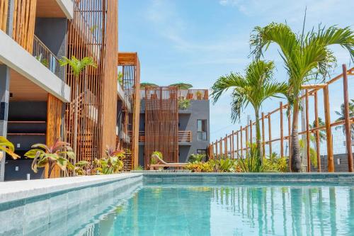 una piscina junto a un edificio con palmeras en Condomínio Essence na Beira Mar de Tatuamunha, Rota dos Milagres, en Tatuamunha