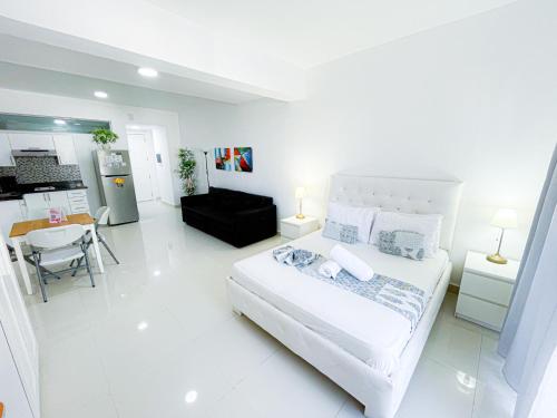 a white bedroom with a bed and a kitchen at DUKASSI SUITES Hotel ROOMS BEACH Bavaro WIFI Parking ROOFTOP POOL & SPA in Punta Cana