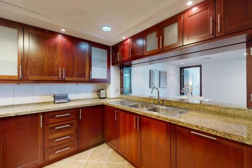 a kitchen with wooden cabinets and a sink at Turia Block A - Vacationer in Dubai