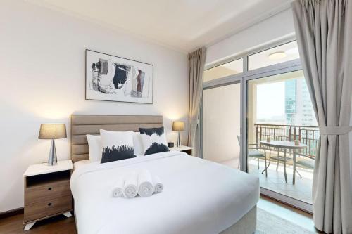 a bedroom with a large white bed and a balcony at Turia Block A - Vacationer in Dubai