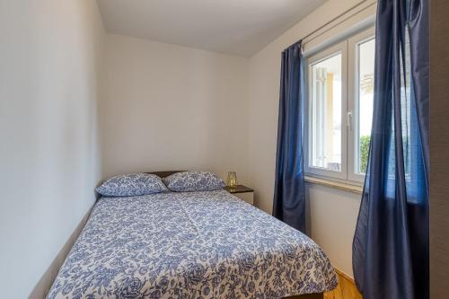 a bedroom with a bed with a blue comforter and a window at Apartment Mirjana in Karigador in Karigador
