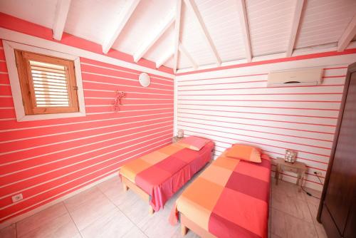 two beds in a room with striped walls at Gite Hibiscus in Pointe-Noire