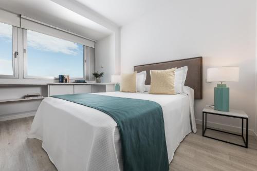 a white bedroom with a large bed and a window at Homeclub Apartment at Plaza Colon in Madrid