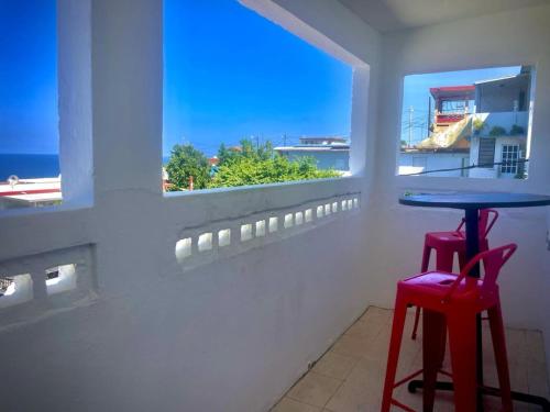 a table and two red stools in a room with a window at Ache Pa Ti II Isabela in Isabela