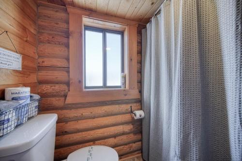 a bathroom with a toilet and a window in a log cabin at Trout Trap at Henry's Lake in Island Park