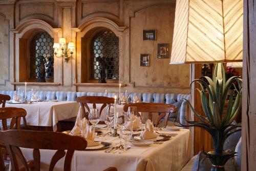 a restaurant with white tables and chairs and a lamp at Wellness & Genuss Resort - Engel Obertal in Baiersbronn