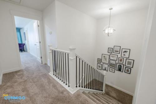 a white hallway with a staircase with pictures on the wall at Pooley Pad in American Fork