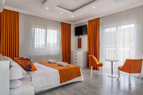 - une chambre avec des rideaux orange, un lit et une table dans l'établissement عظيم Villa, à Trabzon