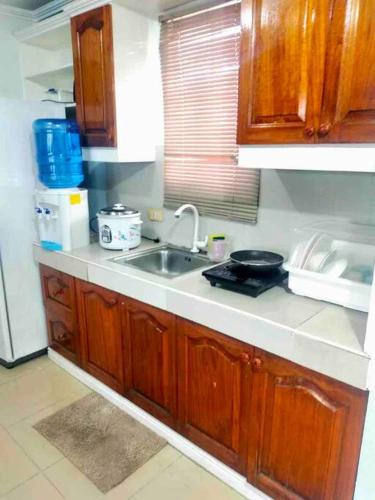 a kitchen with wooden cabinets and a sink at 2-Bedroom/free parking/WiFi in Cainta