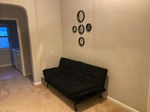 a black couch in a living room with clocks on the wall at Lush 4BR, Large Bckyd, Hot Tub (Tal) in Helotes