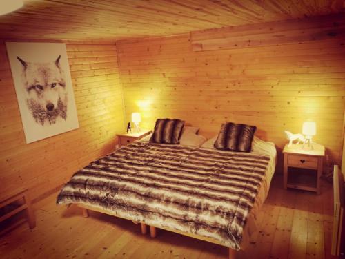 ein Schlafzimmer mit einem Bett in einem Holzzimmer in der Unterkunft The dream catcher -Spa- panoramic sauna- 2 MINUTES FROM THE SLOPES in La Bresse