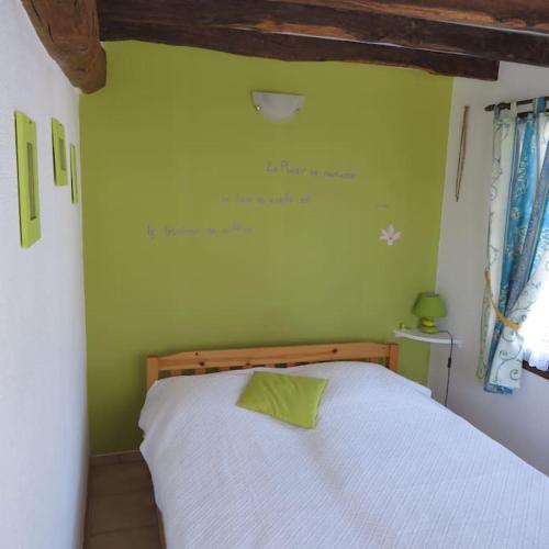 une chambre avec un lit blanc et un mur vert dans l'établissement Les hortensias, à Biville-la-Baignarde