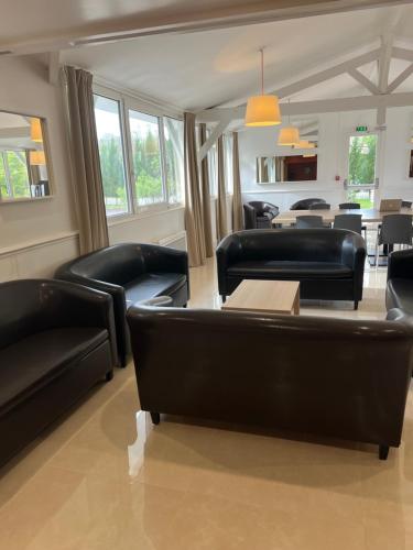 a living room with black leather couches and a table at Budget Hotel Melun Sud - Dammarie Les Lys in Dammarie-lès-Lys