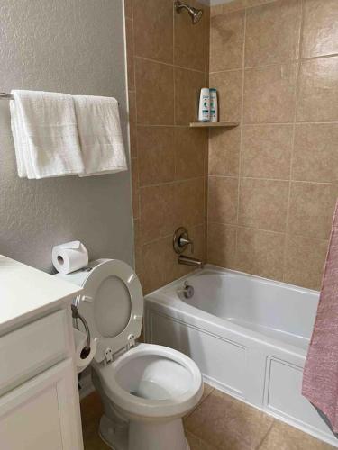 a bathroom with a white toilet and a bath tub at Lxry 4 BR Bckyd, Pool, Hot Tub near attrctns (Tal.) in Helotes