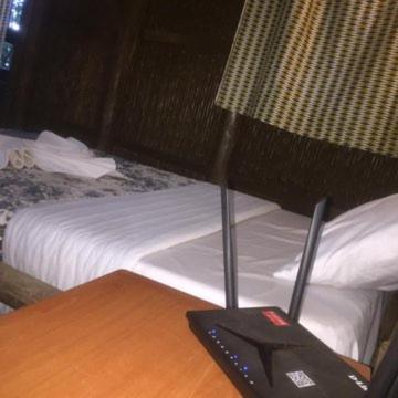 einen Schreibtisch mit Fernbedienung neben einem Bett in der Unterkunft IWACU ECO LODGE in Rwumba