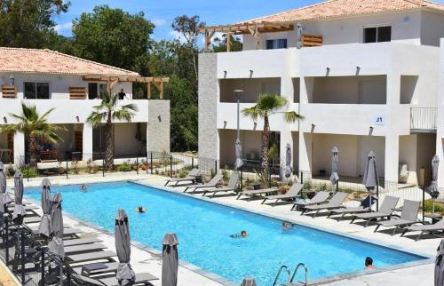 une piscine devant un hôtel avec des chaises longues dans l'établissement T2 VUE MER CORSE N193, à Linguizzetta
