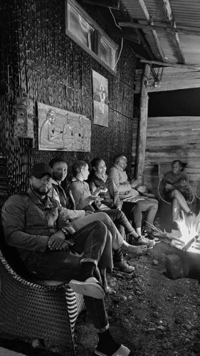 eine Gruppe von Menschen, die neben einem Feuer sitzen in der Unterkunft IWACU ECO LODGE in Rwumba