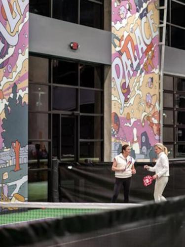 two women standing in front of a building with a mural at Mid-Century Style And Class In Quiet NE Location in Cedar Rapids