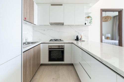 a white kitchen with white cabinets and a stove at Frank Porter - One Park Avenue in Dubai