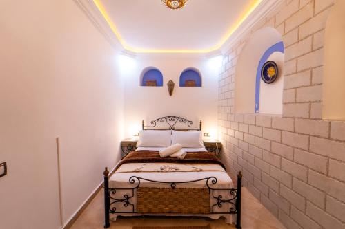 1 dormitorio con 1 cama en una pared de ladrillo en DAR NOKHBA INN, en Chefchaouen