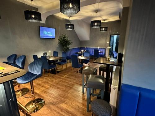a restaurant with blue chairs and tables and a tv at Hotel Neon in Blackpool