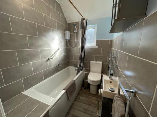 a bathroom with a tub and a toilet and a sink at Raes Cottage Sleeps 2 plus1 in Camelford