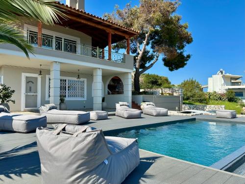 a house with a swimming pool with white furniture next to it at Three Elements in Pefkali